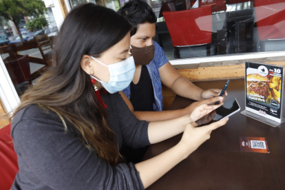 Usuarias de un restaurante en Guayaquil utilizan sus celulares para aceder al menú a través del código QR, eso se hace ahora por bioseguridad.