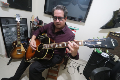 Abraham Cheing, juez y cantante en su despacho, tocando una de sus guitarras.