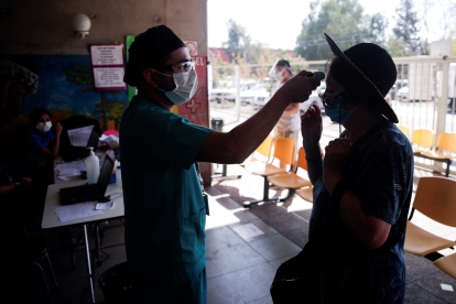 Un enfermero toma la temperatura a una mujer antes de su ingreso a un centro de salud en Santiago (Chile).