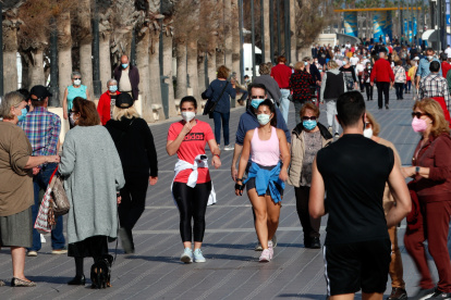 Decenas de personas por el paseo de la playa de la Malvarrosa de Valencia, España.
