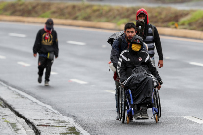 Ciudadanos venezolanos, uno de ellos con discapacidad, transitan por una carretera cercana a Quito (Ecuador).