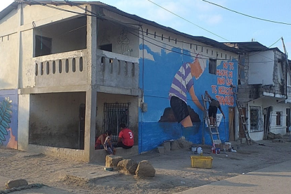 Obras. En la primera pared se muestra la cara de la Valdivia y en la segunda figura, uno de los artistas plasma la figura de un niño, una canoa y el mar.