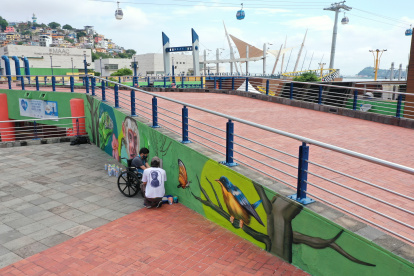 Felipe Arroba pinta un árbol en un mural en el Malecón 2000, junto al pintor Andy Son.