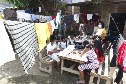 La ropa tendida en los cordeles, topa las cabezas de los niños que acuden al patio de una casa a realizar sus tareas escolares.
