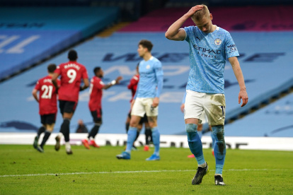 Oleksandr Zinchenko del Manchester City se lamenta, mientras al fondo celebran los jugadores del United.