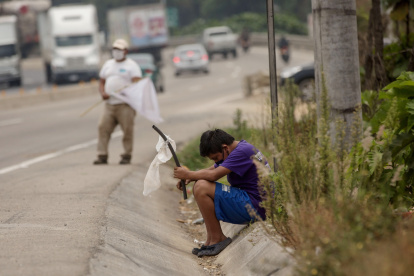Un niño ondea una bandera blanca en la carretera pidiendo ayuda por hambre.