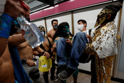 Profesionales de la lucha libre mexicana viajan concienciando del uso del tapabocas, en el metro de Ciudad de México.