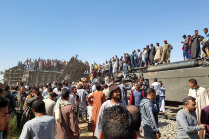 Tahta District (Egypt), 26/03/2021.- People stand atop a turned over train carriage as others inspect the scene of a train crash in Sohag province, Egypt, 26 March 2021. At least 32 people were killed and some 66 injured as two passenger trains collided in the Tahta district in Sohag governorate, the Health Ministry announced. (Egipto) EFE/EPA/STRINGER At least 32 dead in train collision in Sohag