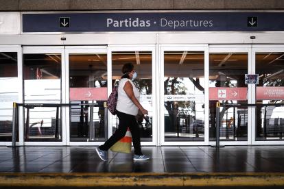 Una mujer camina frente a la puerta cerrada de la sección de "Salidas" del aeropuerto en Buenos Aires (Argentina).