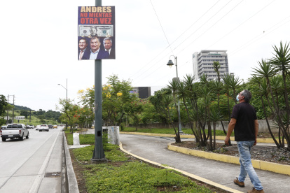 Un ciudadano observa un letrero colgado en la avenida del Bombero, en Guayaquil. Nadie se atribuye su autoría.