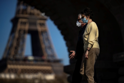 Paris (France), 31/03/2021.- Pedestrians wearing protective face masks enjoy the warm spring weather as they walk across the Bir Hakeim bridge near the Eiffel Tower, hours before French President Emmanuel Macron is due to make a televised address to the nation to announce enhanced measures to fight the spread of Covid19 coronavirus as France faces a third wave of the pandemic, in Paris, France, 31 March 2021. (Francia) EFE/EPA/IAN LANGSDON