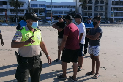 Un agente de Policía dispersa a turistas en la playa de Salinas.