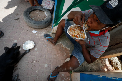Henrique Silva, de 22 años, almuerza tras recibir una donación de comida en la calle da Paz, el 2 de abril de 2021 en la favela de Paraisópolis, en Sao Paulo (Brasil).
