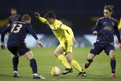 Gerard Moreno (centro) del Villarreal protege el balón ante la marca de Stefan Ristovski (izquierada)