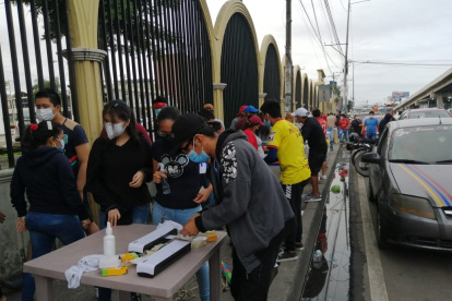 En la medida que llegan más ciudadanos a votar se forman los grupos que buscan plastificar la cédula de votación.