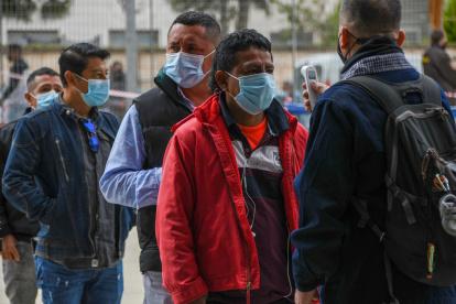 Un empleado le toma la temperatura a una ciudadana ecuatoriana residente en España vota en la segunda vuelta de las elecciones presidenciales de su país este domingo en el Palma Arena de Palma de Mallorca.