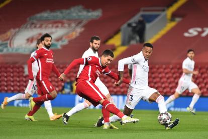 Firmino, del Liverpool, intenta rematar ante la marca del madridista, Militao.