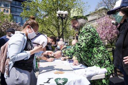 El voluntario Todd Hinden (R) reparte cigarrillos de marihuana a todo aquel que pueda demostrar que ha sido vacunado contra el COVID-19.