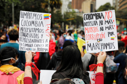 Una mujer sostiene dos carteles durante una protesta en rechazo a la violencia ocurrida en las protestas hoy, en el Parque Nacional de Bogotá (Colombia).