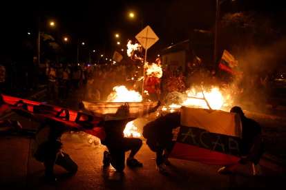 Manifestantes muestran banderas, mientras queman objetos, durante una manifestación contra del gobierno de Iván Duque, este lunes, en Cali (Colombia).