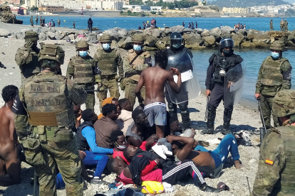 Miembros del Ejército de Tierra y de la Cruz Roja ayudan a un inmigrante que han logrado cruzar uno de los espigones fronterizos de Ceuta.