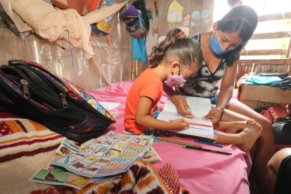 Una niña recibe clases en casa de la mano de su madre. Su hogar no cuenta con Internet.