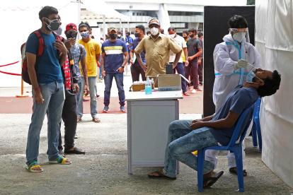 Un trabajador de salud toma una muestra nasal y un hisopo de un hombre para una prueba de COVID-19 en Bangalore, India.