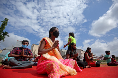 Niños con discapacidades visuales y entusiastas del yoga que usan mascarillas practican la meditación en el Día Internacional del Yoga en Bangalore, India.