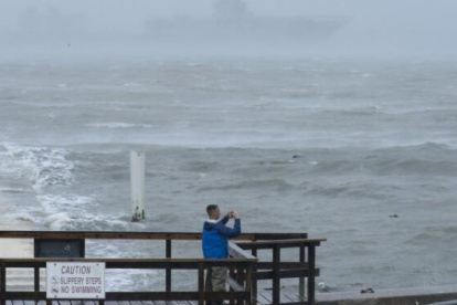 Dos hombres toman fotografías del comportamiento del mar frente a los fuertes vientos.