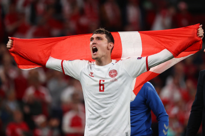 Andres Christensen muestra una bandera danesa luego de la victoria frente a Rusia.