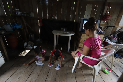 Moisés y Judith, hijos de María Fernanda Orellana, juegan en el piso de su humilde vivienda al no tener labores escolares que hacer porque no están en la escuela.