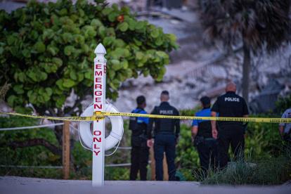 Agentes de la Policía custodian los alrededores del edificio de 12 pisos parcialmente colapsado.