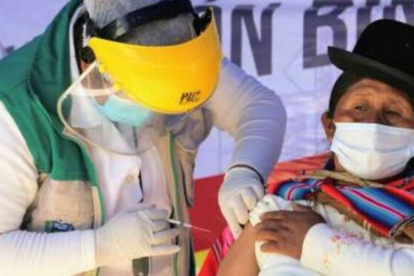 Un médico vacuna a una indígena boliviana.