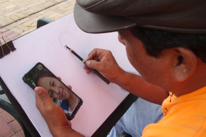 Édgar Jaime pintando un retrato que el cliente le envió por Whatsapp, en estos tiempos de pandemia.