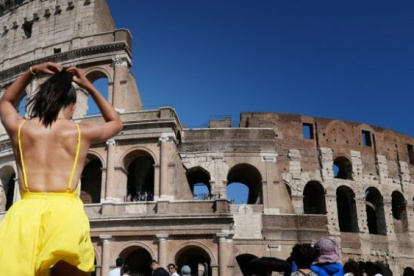 Una turista con ropa ligera visita el Coliseo Romano.