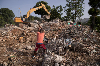 Un hombre recupera varillas de hierro para reutilizar en una área llena de escombros por la caída de un muro durante el terremoto . EFE/ Orlando Barría