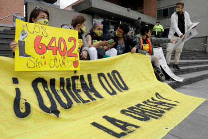 Una mujer muestra un cartel que detalla el número 6.402, cifra aludida a las víctimas de los llamados "falsos positivos".