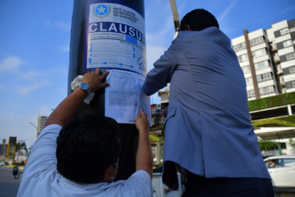 Momento en que el personal del Municipio de Guayaquil pega la sanción en el poste de una valla publicitaria.