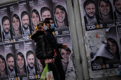 Una pareja camina frente a un cartel con la cara de Leandro Santoro, candidato a Diputado Nacional por el Frente de Todos, el 9 de septiembre de 2021, en la Ciudad de Buenos Aires (Argentina). Argentina volverá a las urnas este domingo para elegir en unas primarias abiertas a los candidatos que competirán en los comicios legislativos de noviembre próximo, un proceso electoral marcado por la pandemia de la covid-19. Unos 34,3 millones de argentinos están convocados para definir con su voto las listas de candidatos que quedarán habilitadas para competir en los comicios del 14 de noviembre, en los que se renovarán 127 de los 257 escaños de la Cámara de Diputados y 24 de las 72 bancas del Senado.