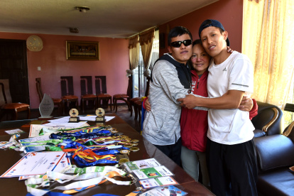 Maribel Calle (c) junto a sus dos hijos, Daniel Simbaña (i), paratleta con discapacidad visual, y Andrés Simbaña, quien además de hermano es guía del deportista en las competencias.