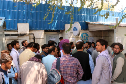 Afganos aguardan afuera de un banco cerrado en Kabul, Afganistán, para intentar retirar dinero.