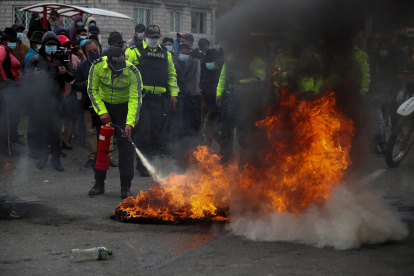 Policías intentan extinguir el fuego de unas barricadas en una carretera, encendido por indígenas que protestan para exigir la derogación del alza en los precios de los combustibles, en Pujilí, provincia de Cotopaxi (Ecuador).