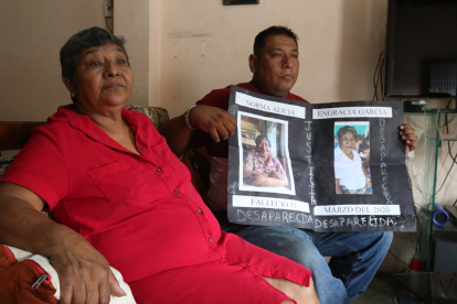 Reclamo. Roberto Farías muestra, junto a su tía, un cartel con la foto de su madre saparecida desde la pandemia.