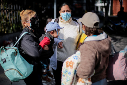 Venezolanos esperan antes de abordar un bus hoy viernes, frente al consulado de su país en Quito.