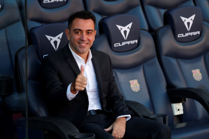 El nuevo entrenador del FC Barcelona, Xavi Hernández, posa en el banquillo del Camp Nou tras finalizar el acto de presentación como entrenador blaugrana.