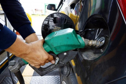 PISTOLA DE DISPENSADOR DE COMBUSTIBLE MIENTRAS LLENA EL TANQUE DE GASOLINA DE UN AUTO |