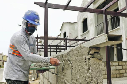 TRABAJADOR ALBAÑIL MIENTRAS CONSTRUYE UNA CASA EN UN PROYECTO HABITACIONAL |