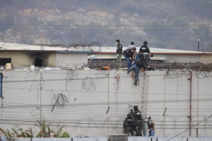 Sobre un muro del pabellón 2 se observa cómo se realizan pericias alrededor de un cadáver.
