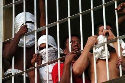 Un grupo de personas privadas de la libertad, tras las rejas.