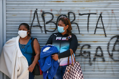 Dos mujeres permanecen frente a un rejado en el que se lee "Aborta", cerca de los exteriores de la Asamblea Nacional, el 1 de diciembre de 2021, en Quito (Ecuador).